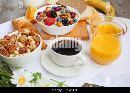 Healthy breakfast with muesli, fruits, berries, nuts, coffee, eggs, honey, oat grains and other on wooden background Stock Photo