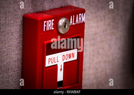 Manual fire alarm activation pull station on wall - signage reading: “FIRE ALARM” and “PULL DOWN”. Stock Photo
