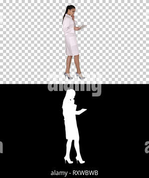 Woman doctor using tablet pc and walking, Alpha Channel Stock Photo