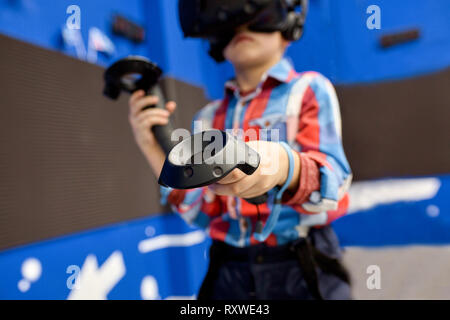 modern technology, gaming and people concept - boy in virtual reality headset or 3d glasses playing videogame at game centre Stock Photo