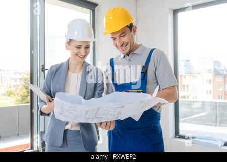Construction worker and architect looking at plan on site Stock Photo