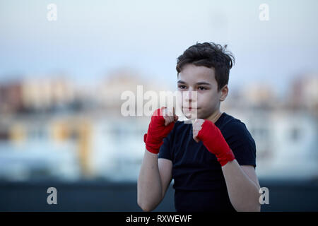 Young fighter training on the roof with buildings in blurred background Stock Photo