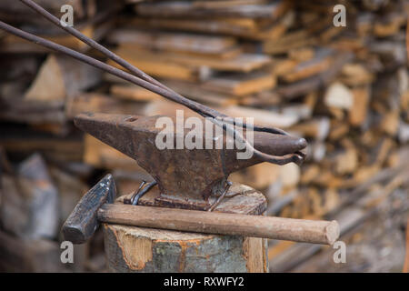 Hammer and bolt tongs on a rusty iron anvil outdoors Stock Photo