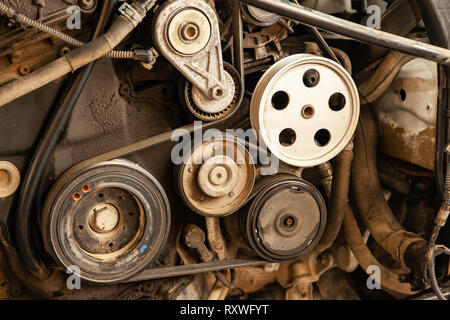 Close up shot of the pulley system and drive belt on a powerful diesel or gasoline used engine with parts of the car and vehicles with dirty oil on th Stock Photo