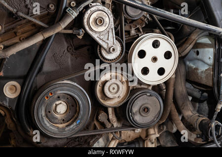Close up shot of the pulley system and drive belt on a powerful diesel or gasoline used engine with parts of the car and vehicles with dirty oil on th Stock Photo