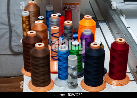 A large number of reels with colored threads in a workshop for sewing and hauling textiles for the automotive industry and industry Stock Photo