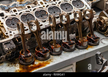 Part of the engine removed from a used car for repairing silver metal and aluminum with six pistons in oil on a workbench in a vehicle repair shop Stock Photo