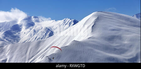 Panoramic view on speed flying in sunlit snowy mountains. Caucasus Mountains. Georgia, region Gudauri at winter. Stock Photo