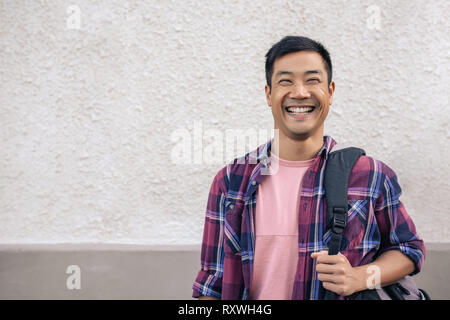 Young Asian man standing outside in the city and laughing Stock Photo