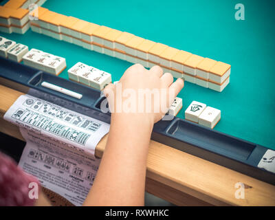 Japanese festival in Moscow. Young people playing mahjong asian tile-based game. Table gambling close up view Stock Photo