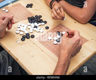 People playing chinese boardgame. People Playing Mahjong Asian Tile-based Game. Table Gambling top viewThe game of go view from above. Stock Photo