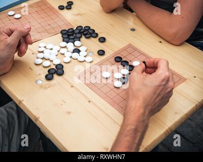 People playing chinese boardgame. People Playing Mahjong Asian Tile-based Game. Table Gambling top viewThe game of go view from above. Stock Photo