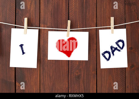 i love dad written in a notes hanging on a clothesline on a dark wooden  background. Stock Photo