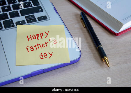 Laptop and stick note with happy fathers day written on wooden table Stock Photo