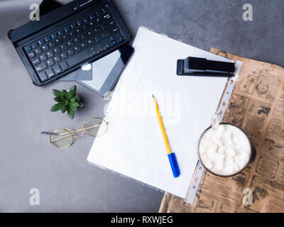 coffee with pen, white papper, glasses, stapler, cactus, coffee and laptop, credit card on concrete table with newspaper Stock Photo