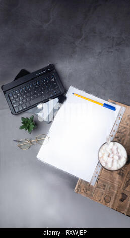 coffee with pen, white papper, glasses, stapler, cactus, coffee and laptop, credit card on concrete table with newspaper Stock Photo