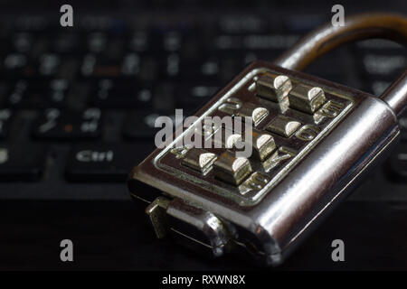 Old Password Key Lock placed on the black notebook keyboard in darkness. The concept of password security in computer systems. Stock Photo