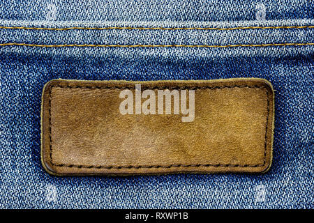 Blank brown leather label on vintage blue jeans. Suitable for backgrounds, articles about fashion clothing. Stock Photo