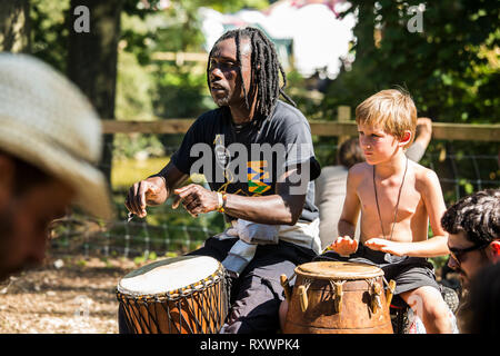 Festival goers attend an outdoor drumming workshop in the woods at Into the Wild festival, Kent, UK Stock Photo