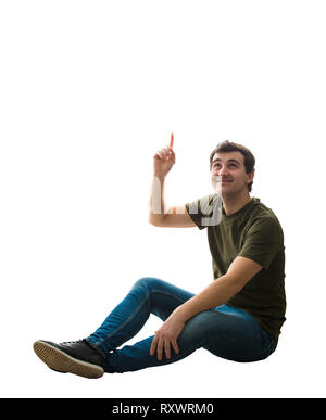 Casual young man sitting on the floor pointing forefinger up over head showing to something. Happy positive guy relaxed mood idea concept isolated ove Stock Photo