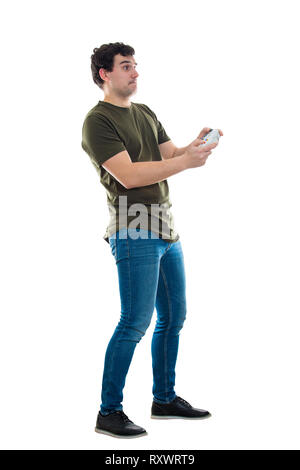 Addicted young man playing video games isolated over white background. Excited guy stand all ears holding a joystick console looking attentive try to  Stock Photo