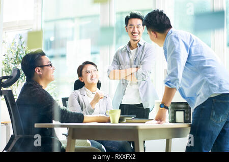 group of four happy young asian corporate people teammates meeting discussing business in office. Stock Photo