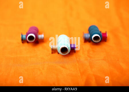 Picture of Colored thread and bobbins. Isolated on the yellow background. Stock Photo