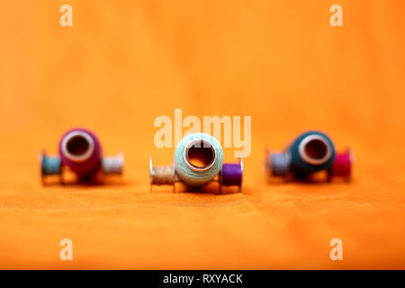 Photo of Colored thread and bobbins. Isolated on the yellow background. Stock Photo