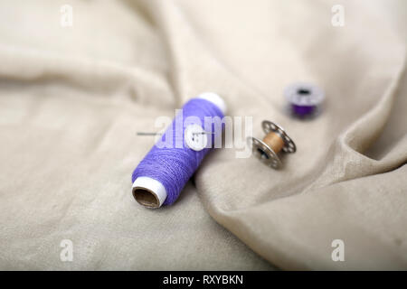 Picture of Purple thread, button and bobbin on the cloth. Stock Photo