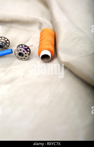 Photo of orange thread, needle ripper and bobbin on the cloth. Stock Photo