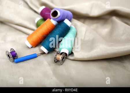 Photo of multicolored thread, needle ripper and bobbin on the cloth. Stock Photo