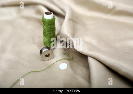 Picture of thread and needle attached in cloth with green Sewing thread and bobbin. Stock Photo