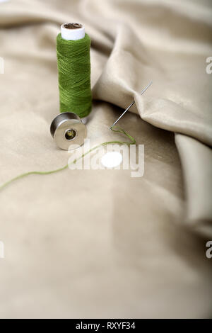 Picture of needle attached in cloth with green Sewing thread and bobbin. Stock Photo