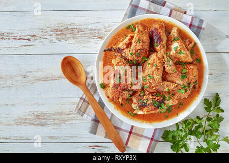 chargrilled Chicken stewed in creamy spicy Coconut milk gravy, kuku paka, served on a white plate on an old wooden table, view from above, close-up, c Stock Photo