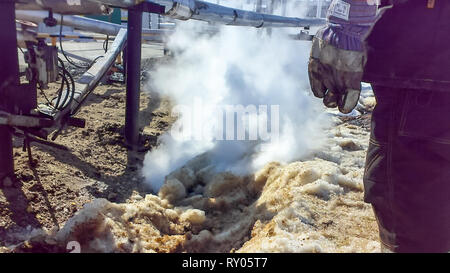 Spilled oil on sandy soil near pipelines and process equipment. Oil leaks during operation and repair Stock Photo