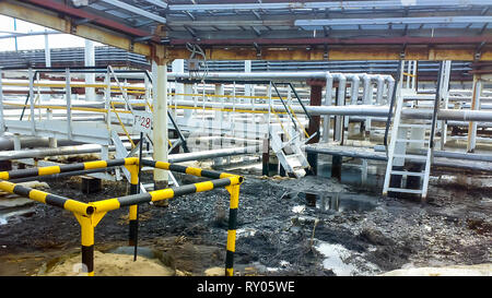 Spilled oil on sandy soil near pipelines and process equipment. Oil leaks during operation and repair Stock Photo