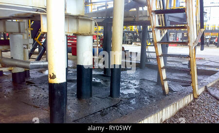 Spilled oil on sandy soil near pipelines and process equipment. Oil leaks during operation and repair Stock Photo