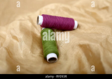 Picture of two sewing thread on the golden cloth. Stock Photo