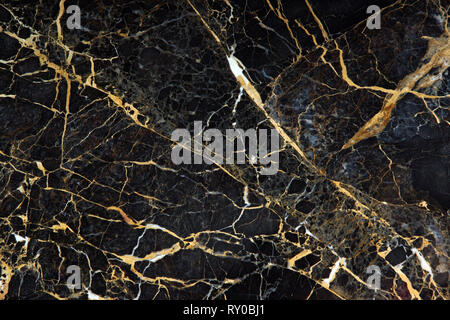 The surface of the slab of dark expensive marble with yellow and white veins is called New Portoro. Stock Photo