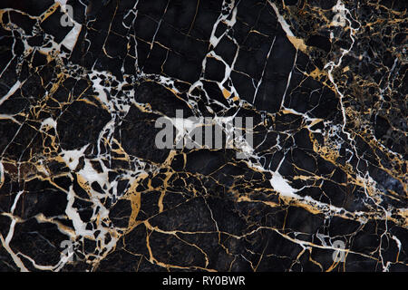 Drawing on the surface of a slab of black marble with yellow and white veins is called New Portoro. Stock Photo
