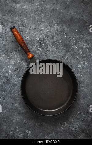 Empty round pan with wooden handle on dark stone background top view Stock Photo