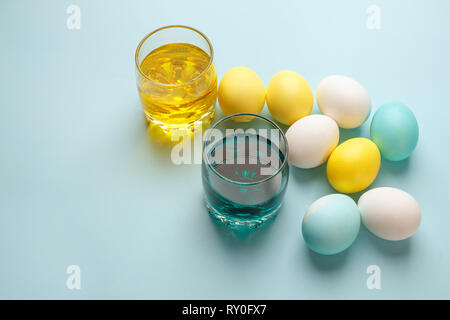 Painting Easter eggs minimal concept, colorful eggs and glass with ink on blue background, modern easter holiday diy Stock Photo