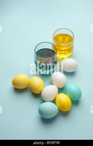 Painting Easter eggs minimal concept, colorful eggs and glass with ink on blue background, modern easter holiday diy Stock Photo