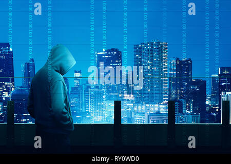 Rear view of hacker in black hoodie standing on the building terrace looking at cityscapes at night with digital binary code background Stock Photo