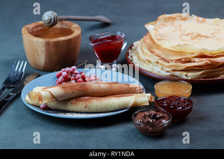 pancakes with berries, jam, honey and chocolate, sprinkled with powdered sugar and cinnamon Stock Photo