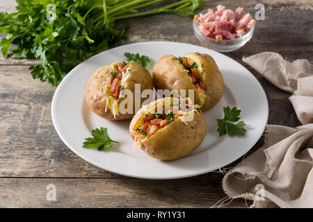 Stuffed potatoes with bacon and cheese on plate on wooden table Stock Photo