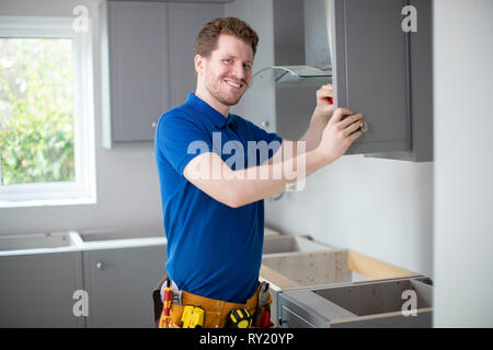 Portrait Of Carpenter Installing Luxury Modern Fitted Kitchen Stock Photo