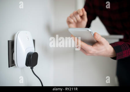 Man Controlling Smart Plug Using App On Mobile Phone Stock Photo