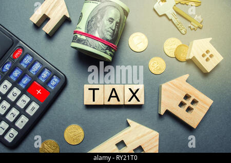 Wooden houses, a calculator, keys, coins and blocks with the word Tax. Property taxes. Calculation of interest on housing tax. Penalty, arrears. Regis Stock Photo