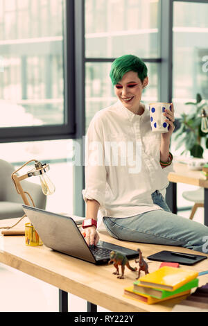 Delighted happy woman sitting on the table Stock Photo
